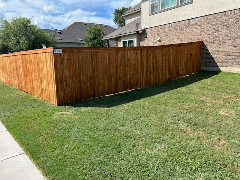 Wooden privacy fence enclosing a backyard next to a house and sidewalk