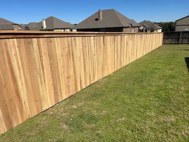 Wooden backyard privacy fence beside a grassy lawn under a clear sky