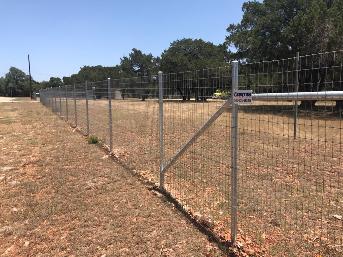 Chain-link fence along a dry field under a clear blue sky