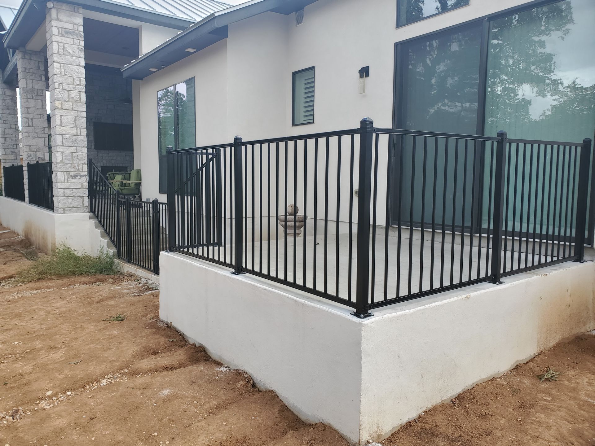 Modern house exterior with a white patio and black metal railing along the deck