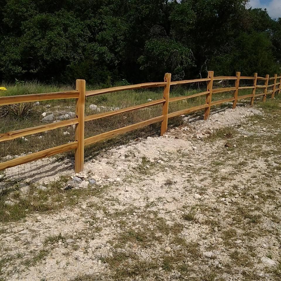 Wooden fence along a sandy dirt path with trees in the background