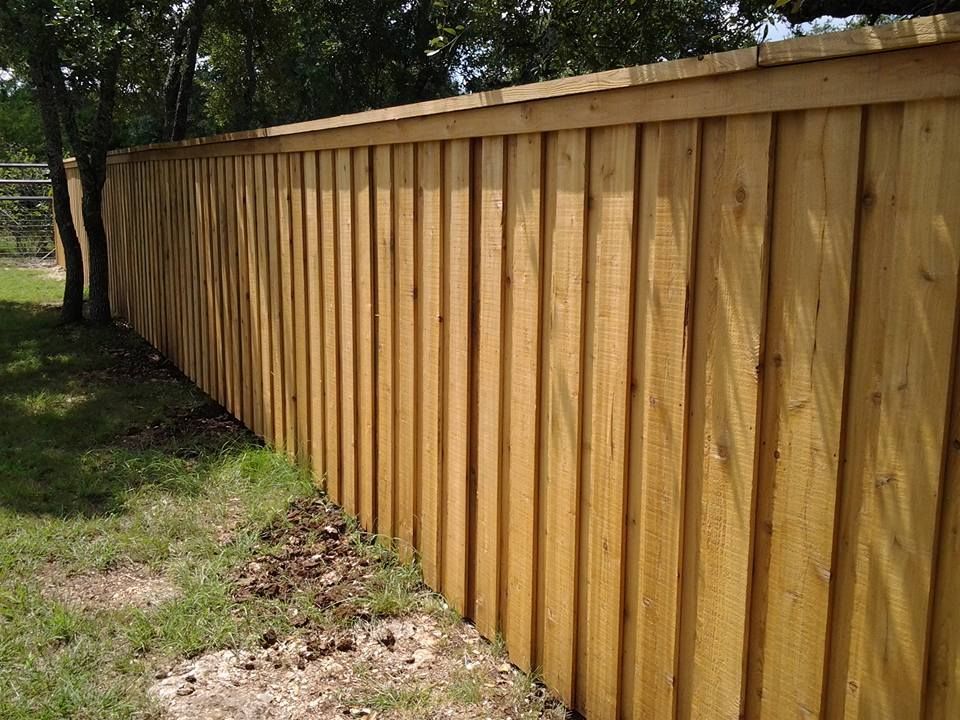 Wooden privacy fence running along a grassy yard beside trees