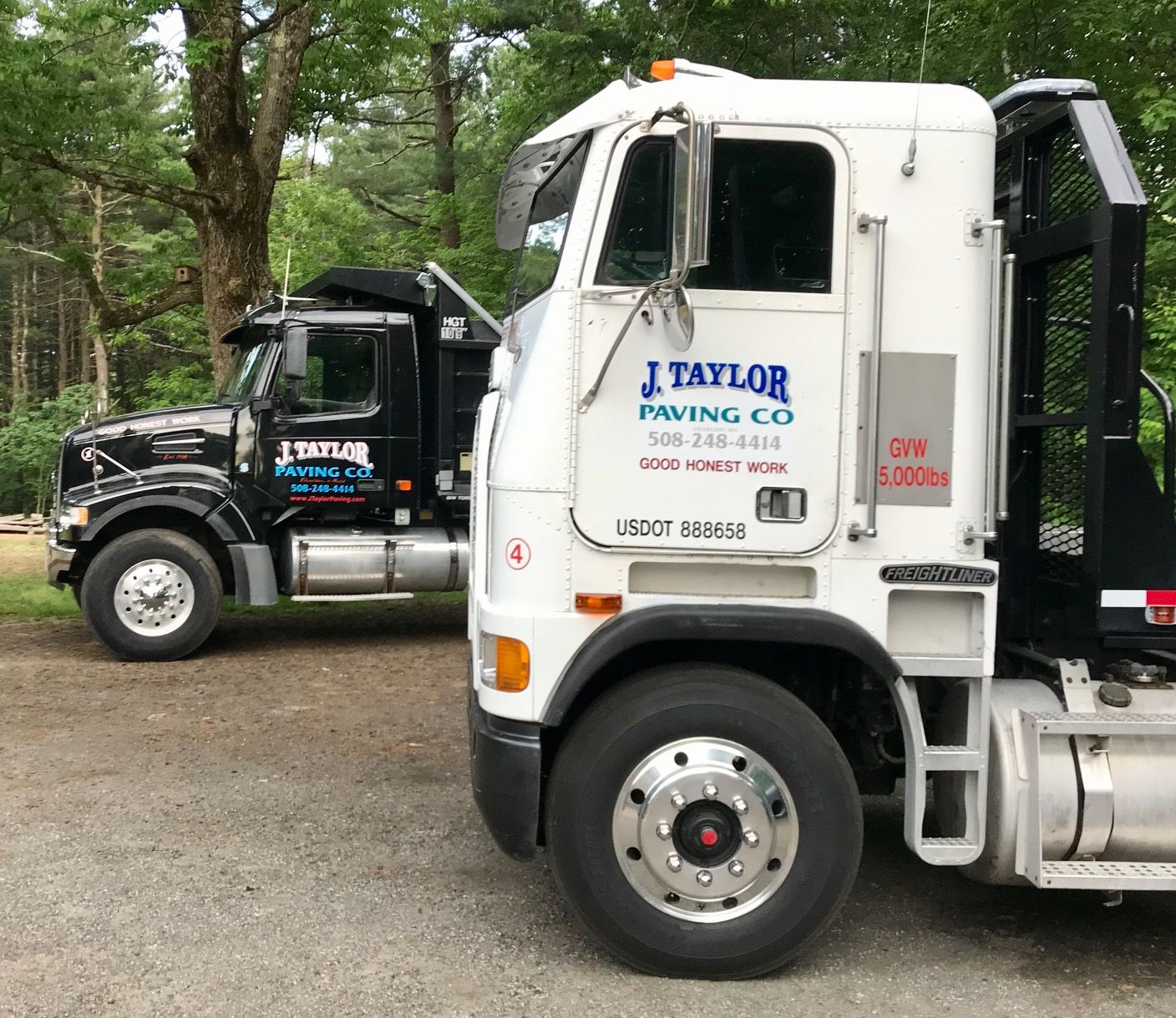 Two trucks are parked next to each other on a dirt road.