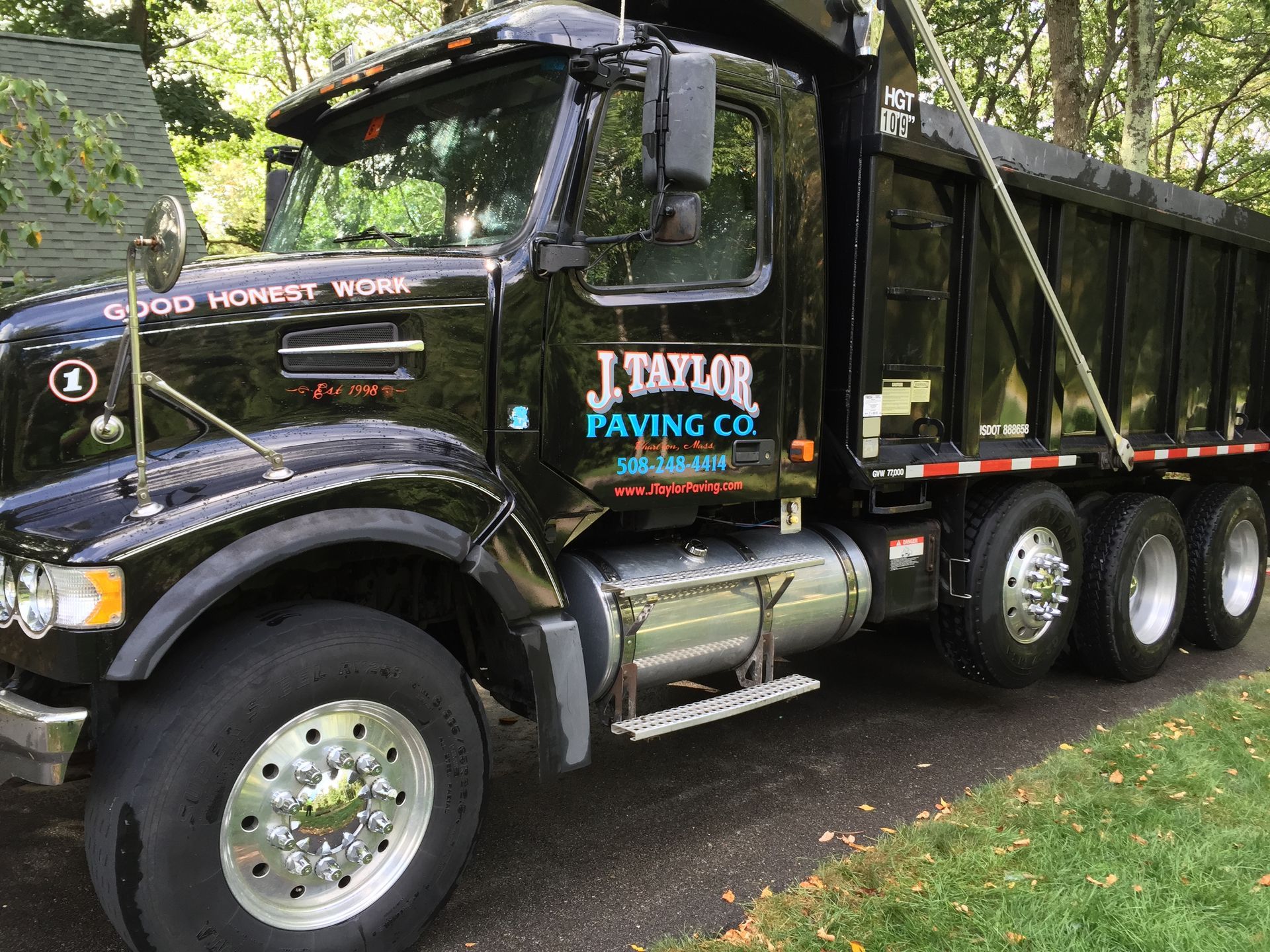 A black dump truck is parked on the side of the road.