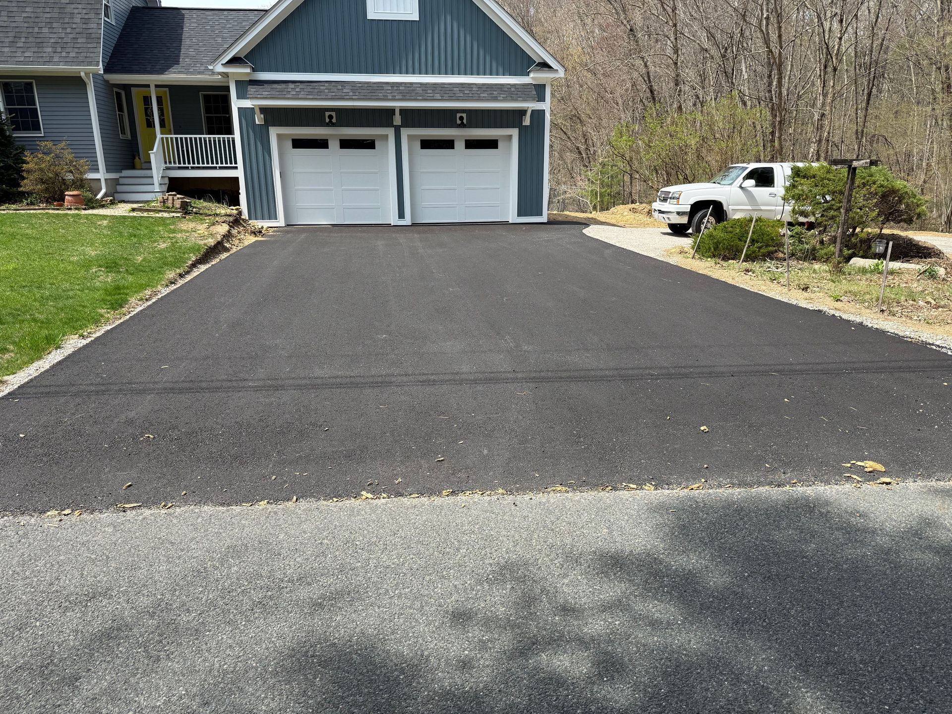 A driveway leading to a house with two garage doors and a truck parked in front of it.