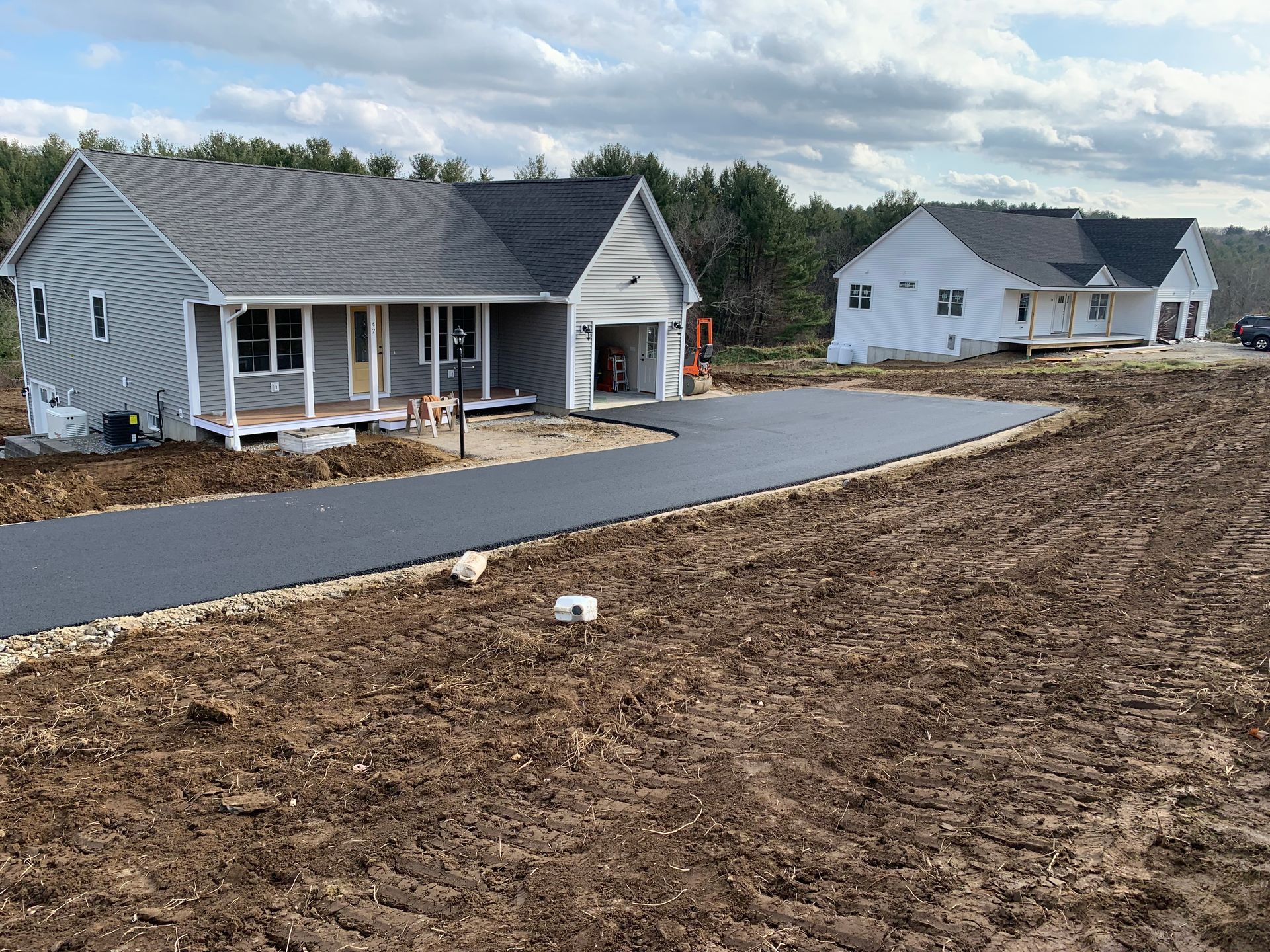 A house is sitting on top of a dirt field next to a road.
