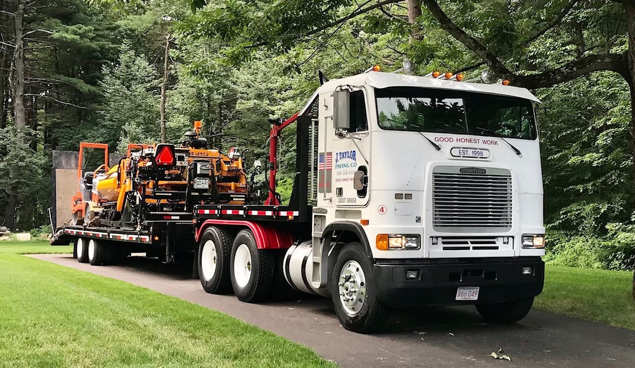 A white semi truck is driving down a road with a trailer attached to it.