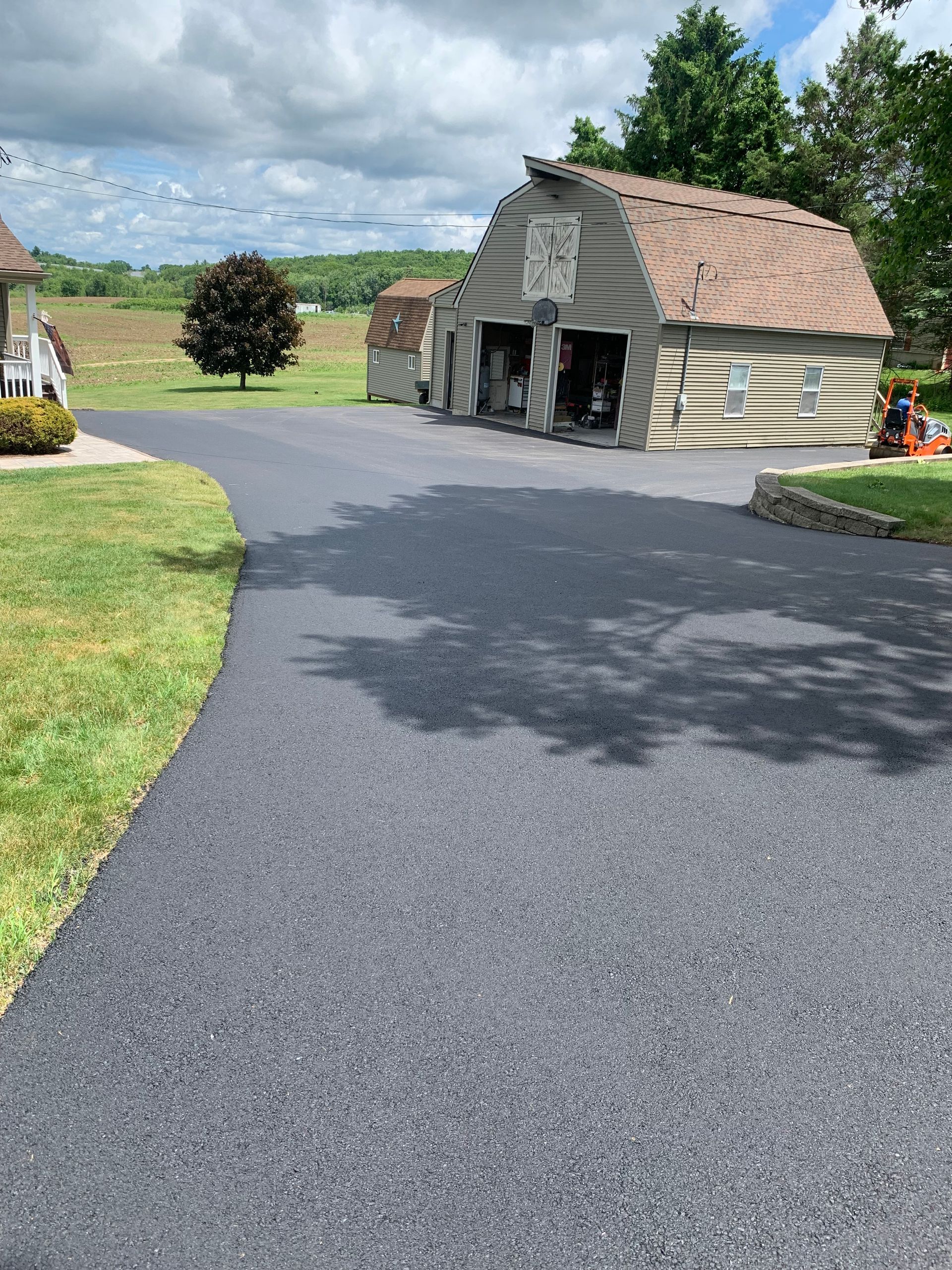A driveway leading to a barn with a tractor parked in front of it.