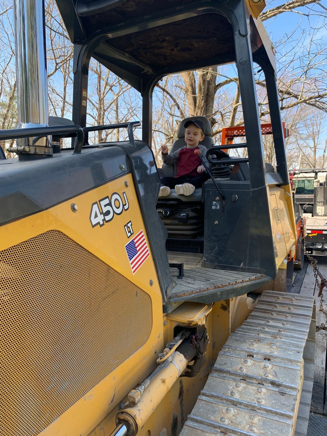 A little boy is sitting in the driver 's seat of a bulldozer.