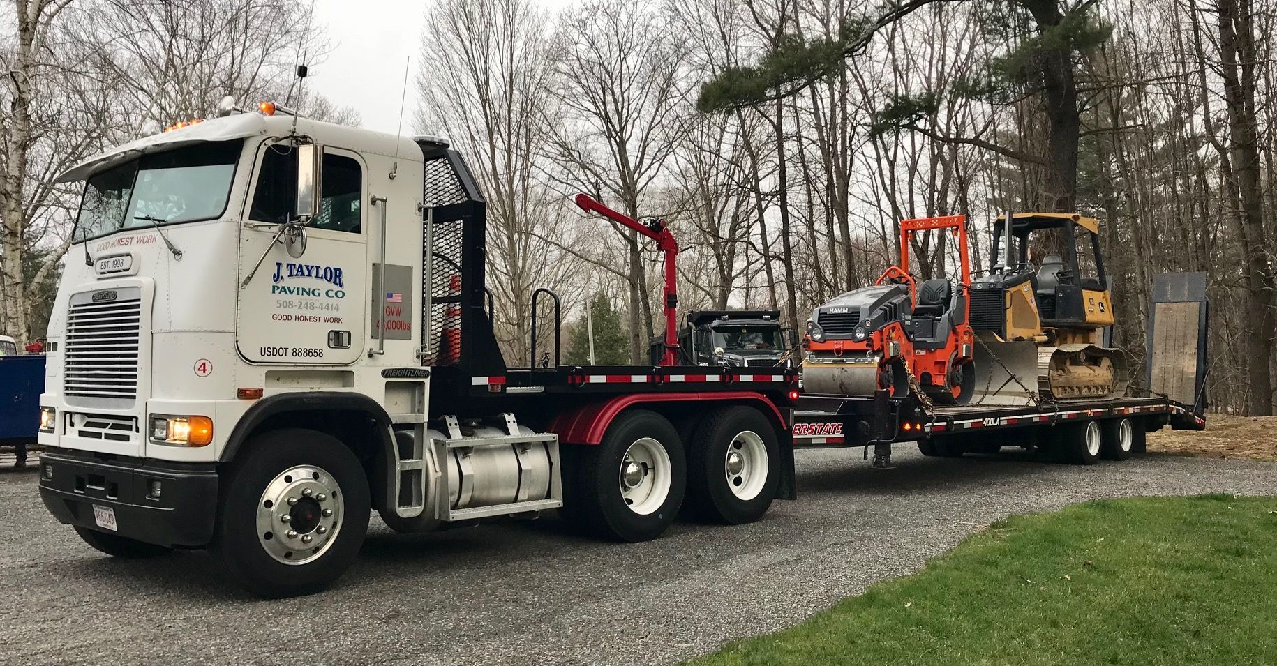 A semi truck is towing a trailer with a bulldozer on it.