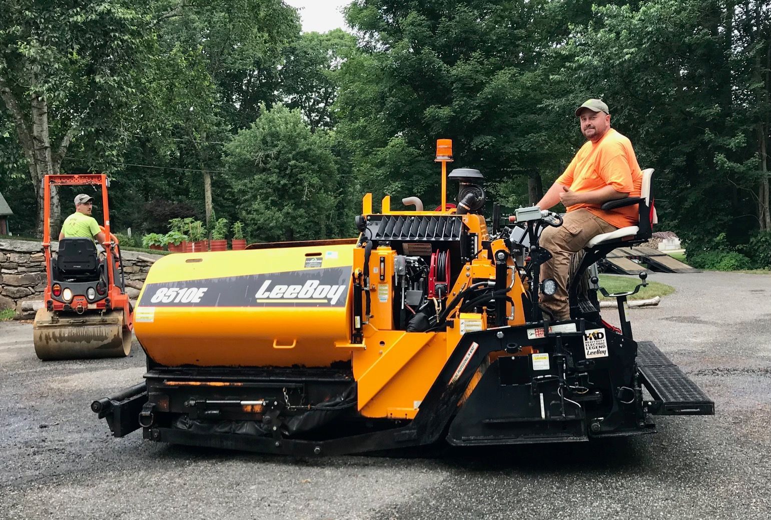 A man is sitting on a yellow asphalt paving machine.