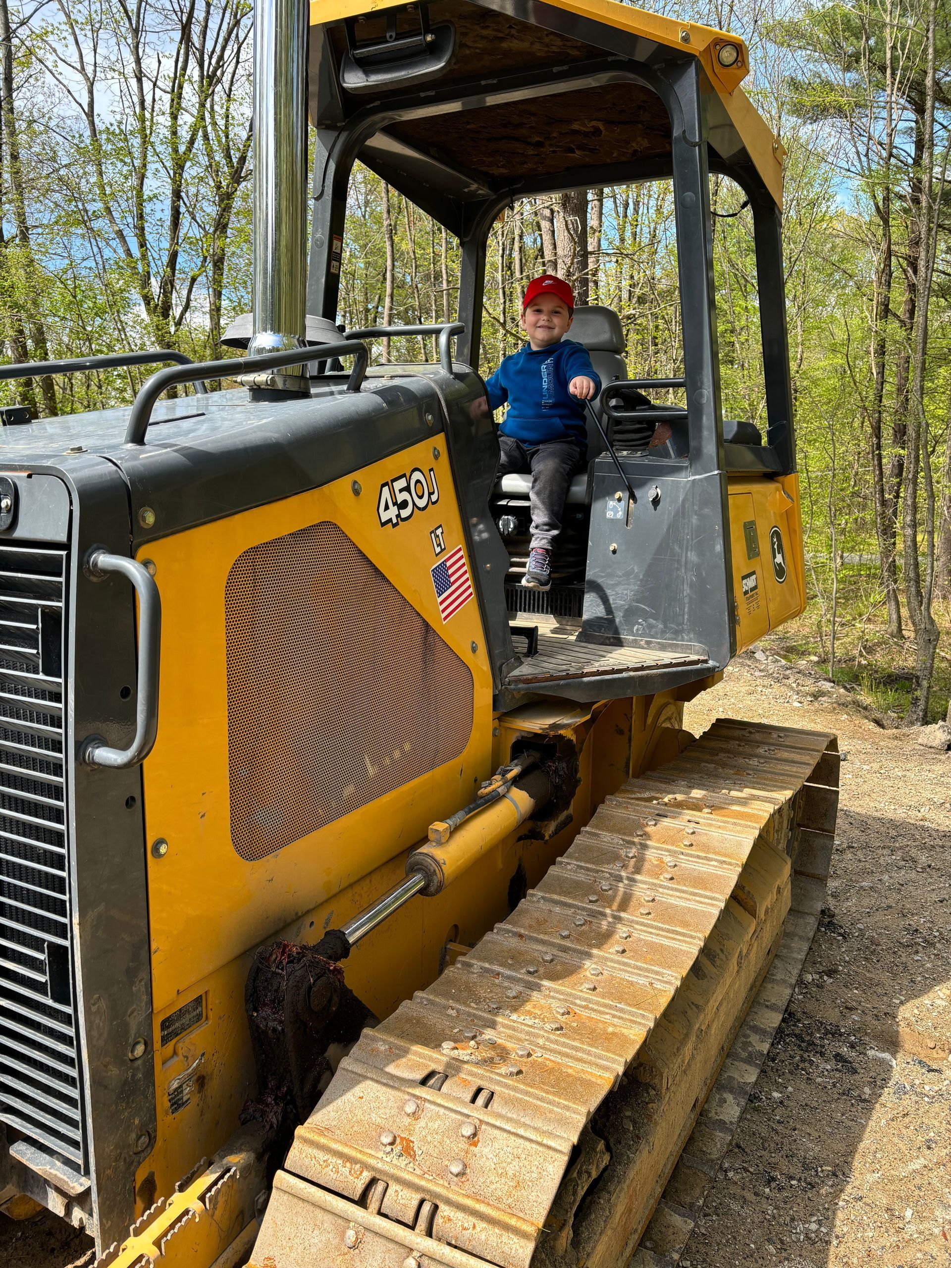 A young boy is riding a bulldozer on a dirt road.