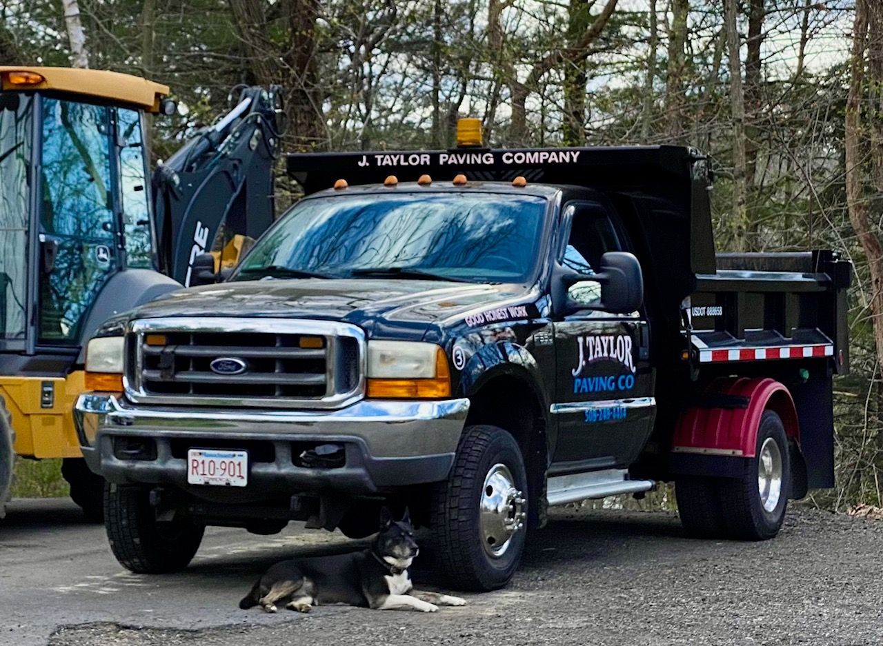A dump truck is parked next to a yellow tractor.