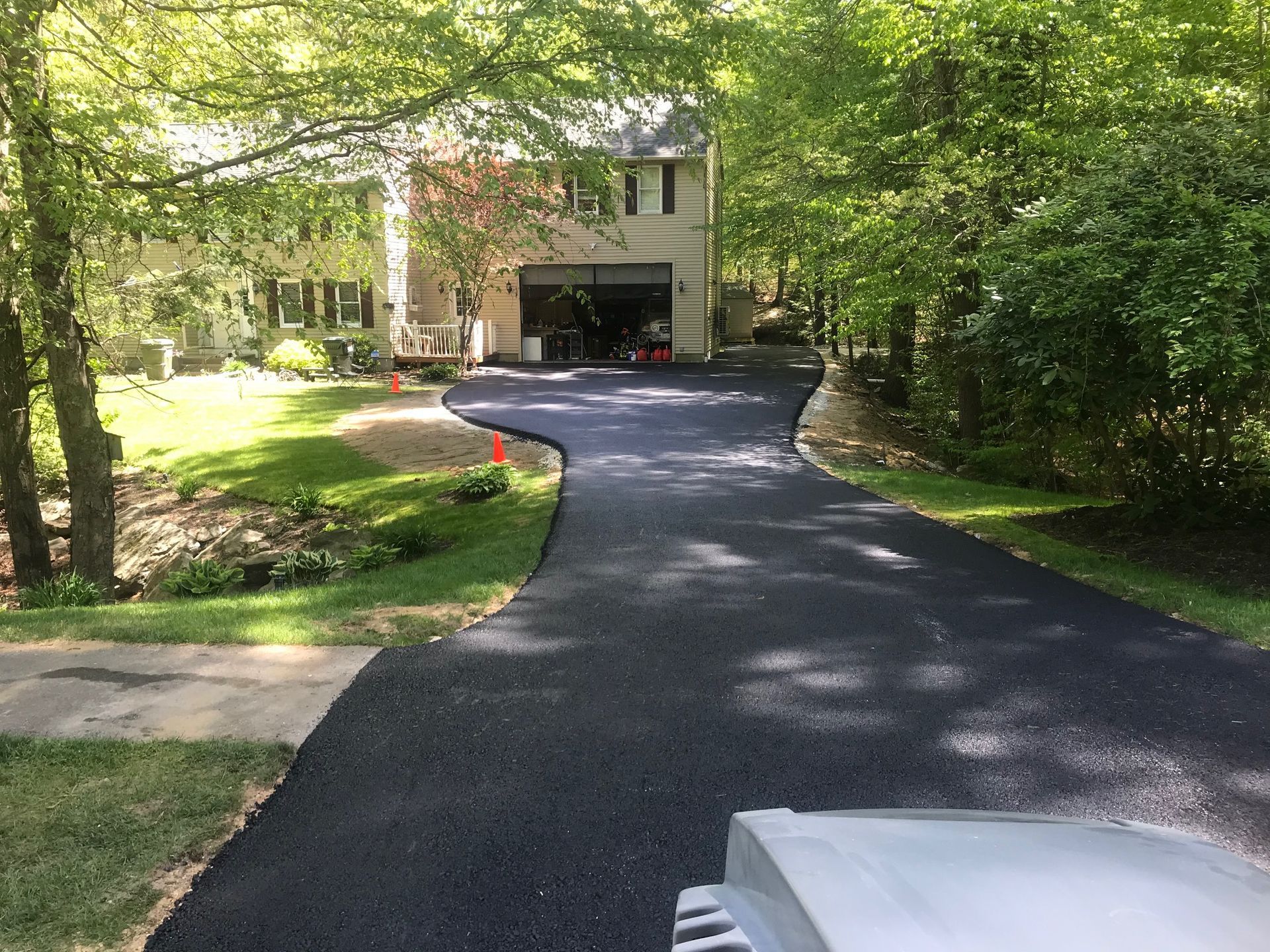A driveway leading to a house surrounded by trees and grass.