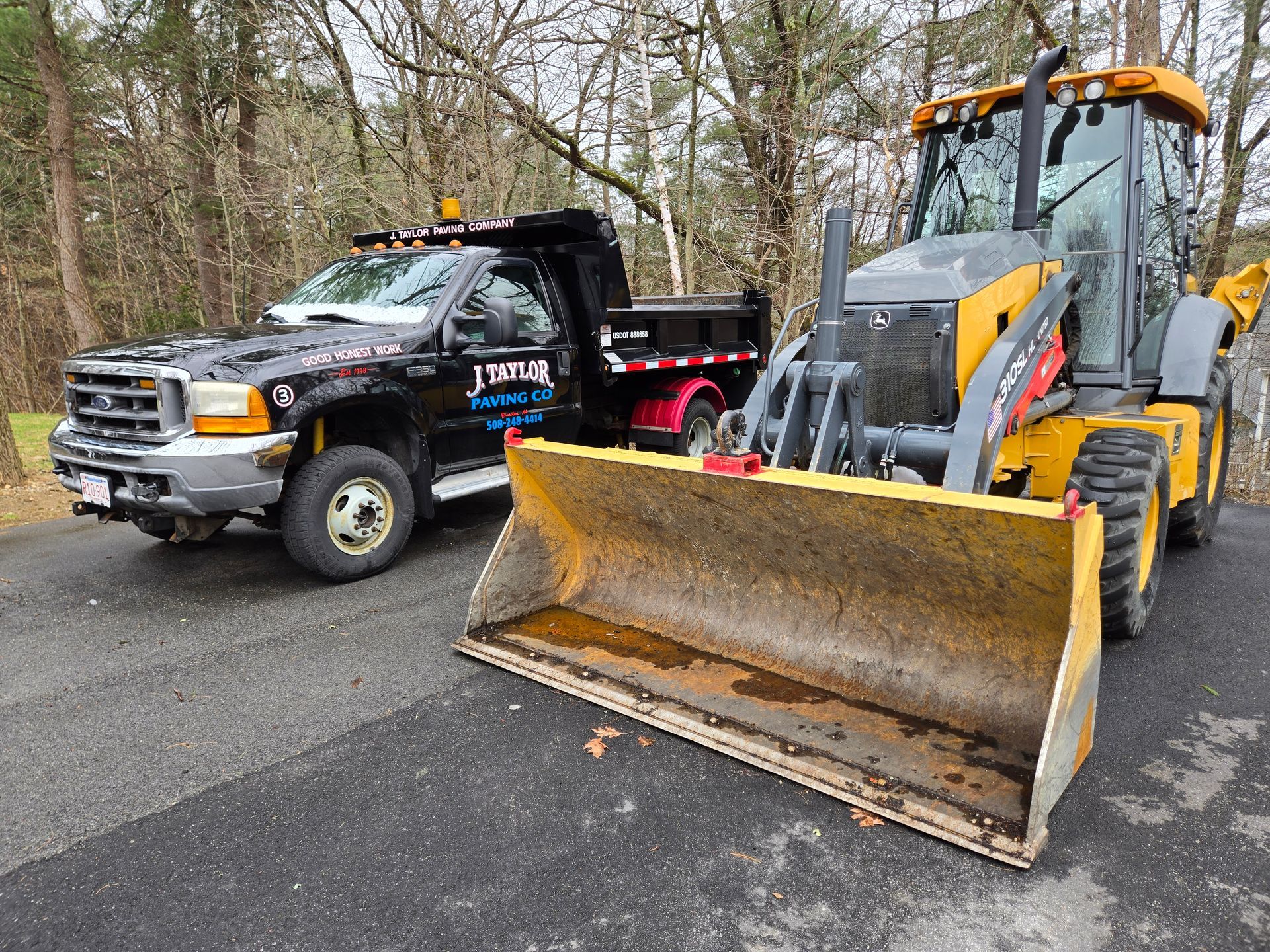 A tow truck and a bulldozer are parked on the side of the road.