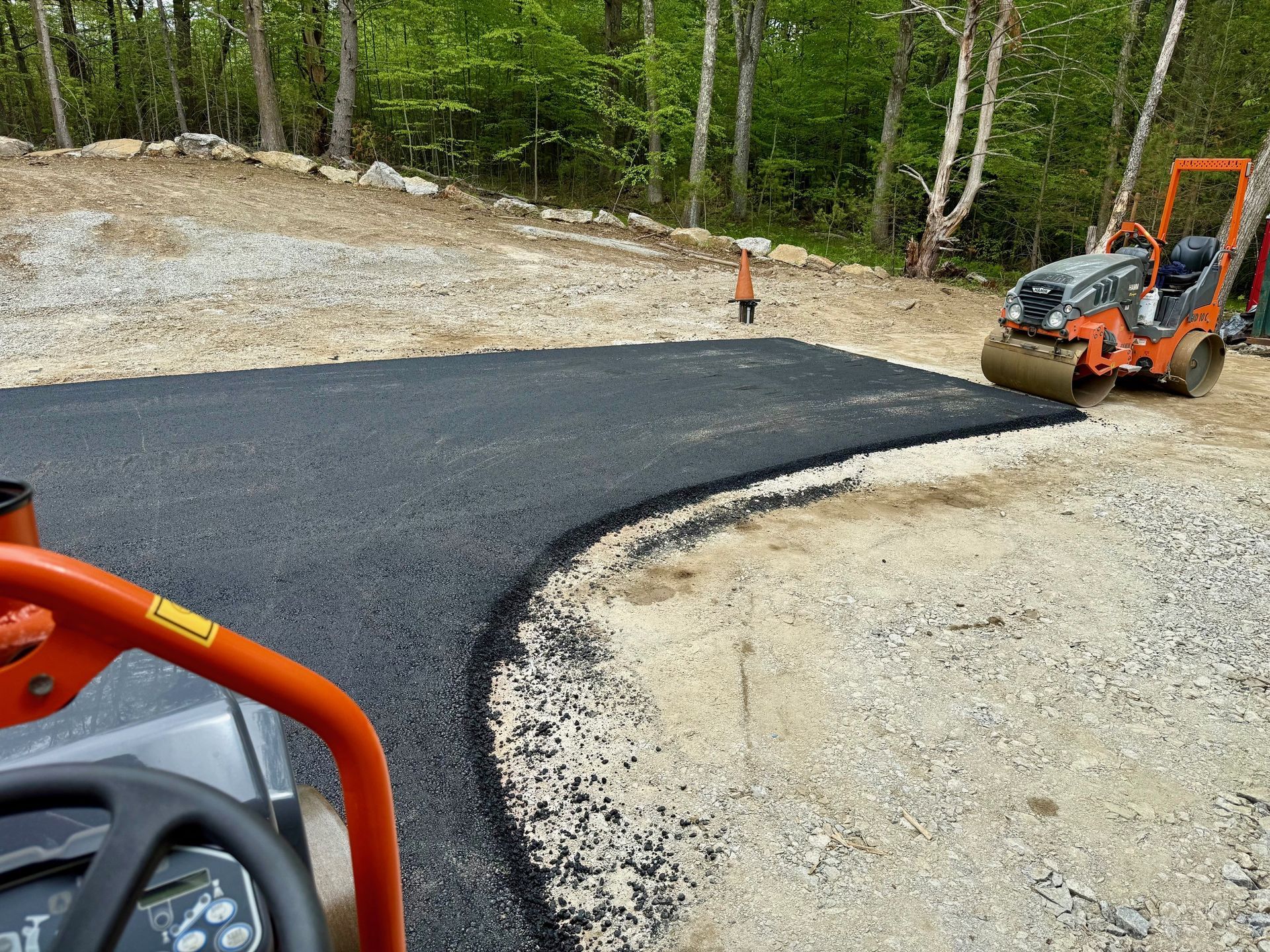 A roller is rolling asphalt on a curvy road.