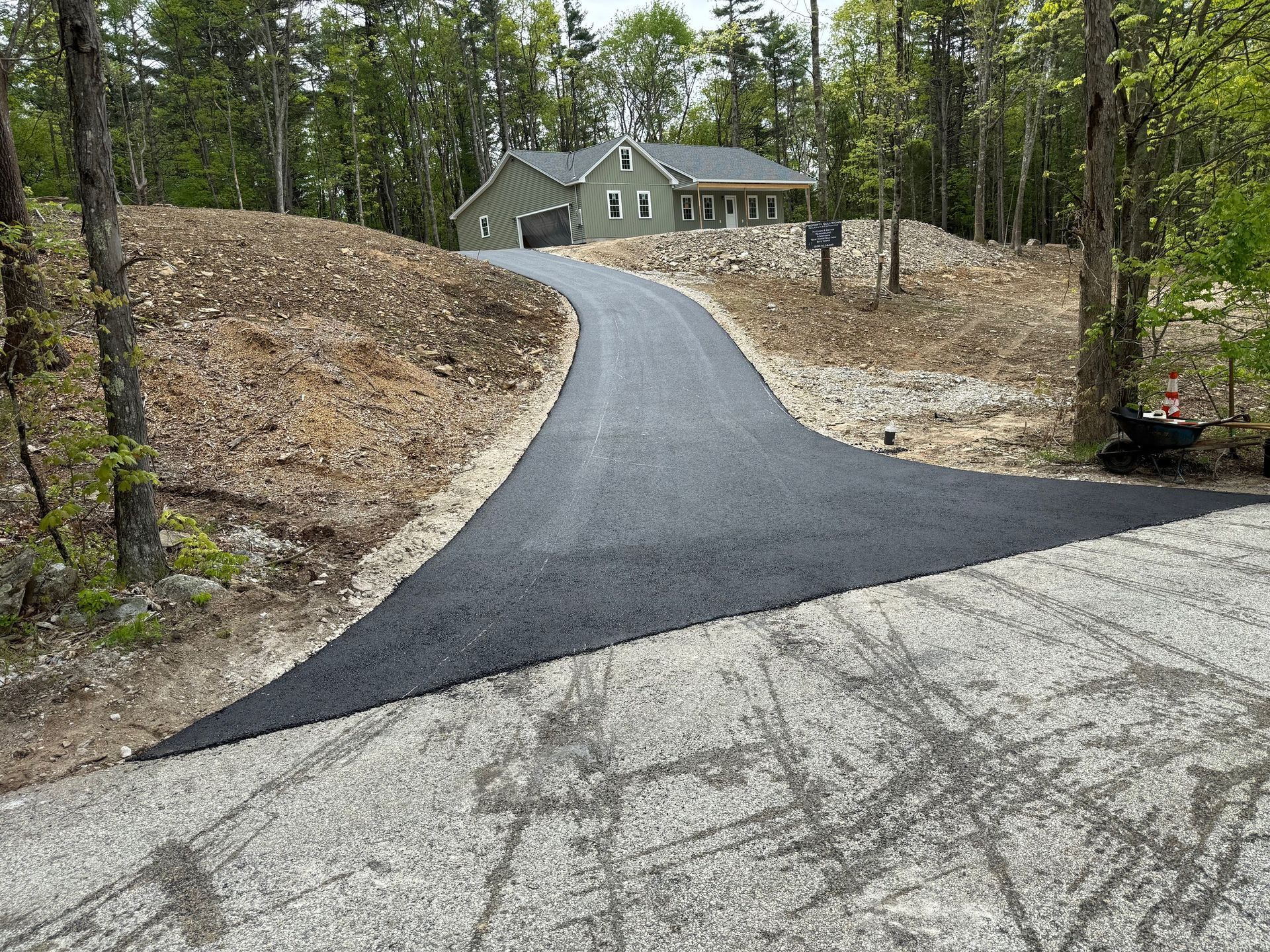A newly paved driveway leading to a house in the woods.