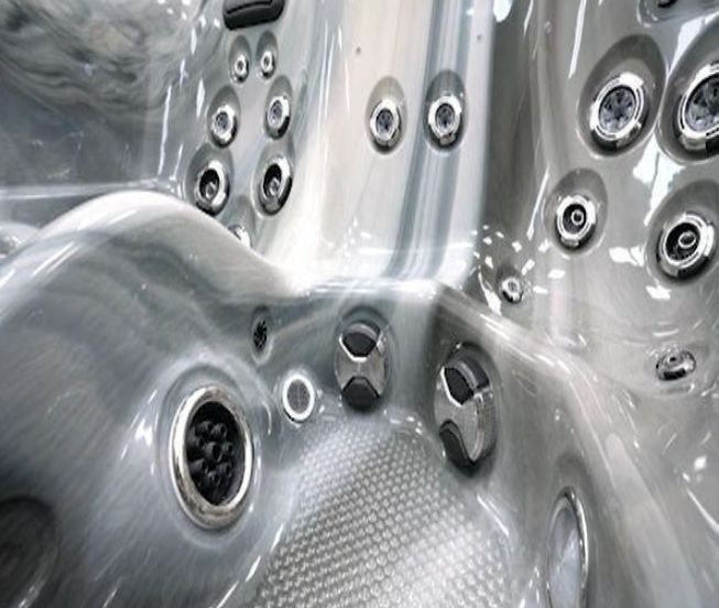 Close-up of a gray hot tub interior with various water jets and control buttons.