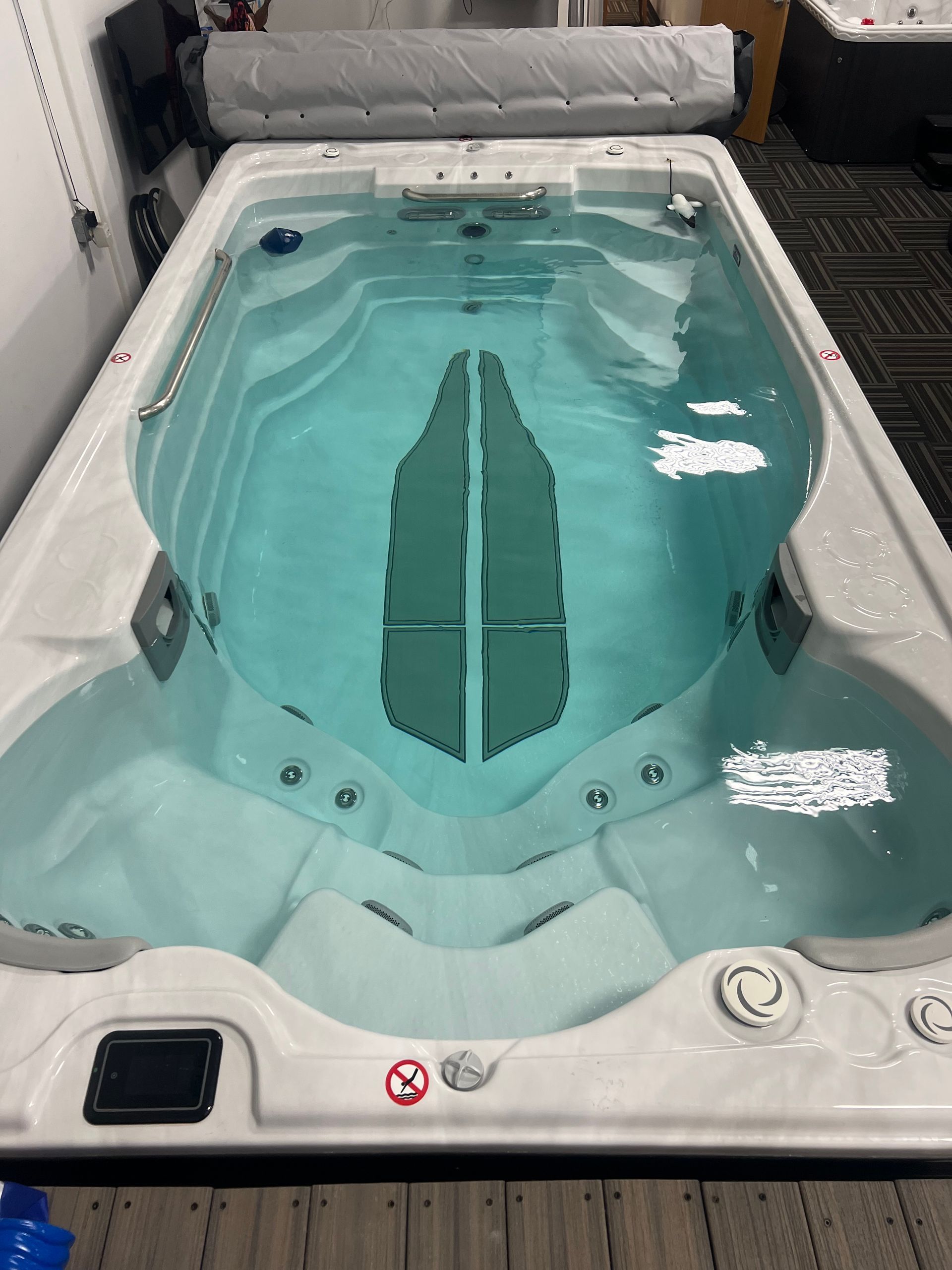 White rectangular swim spa with numerous jets, interior step, and black headrests.