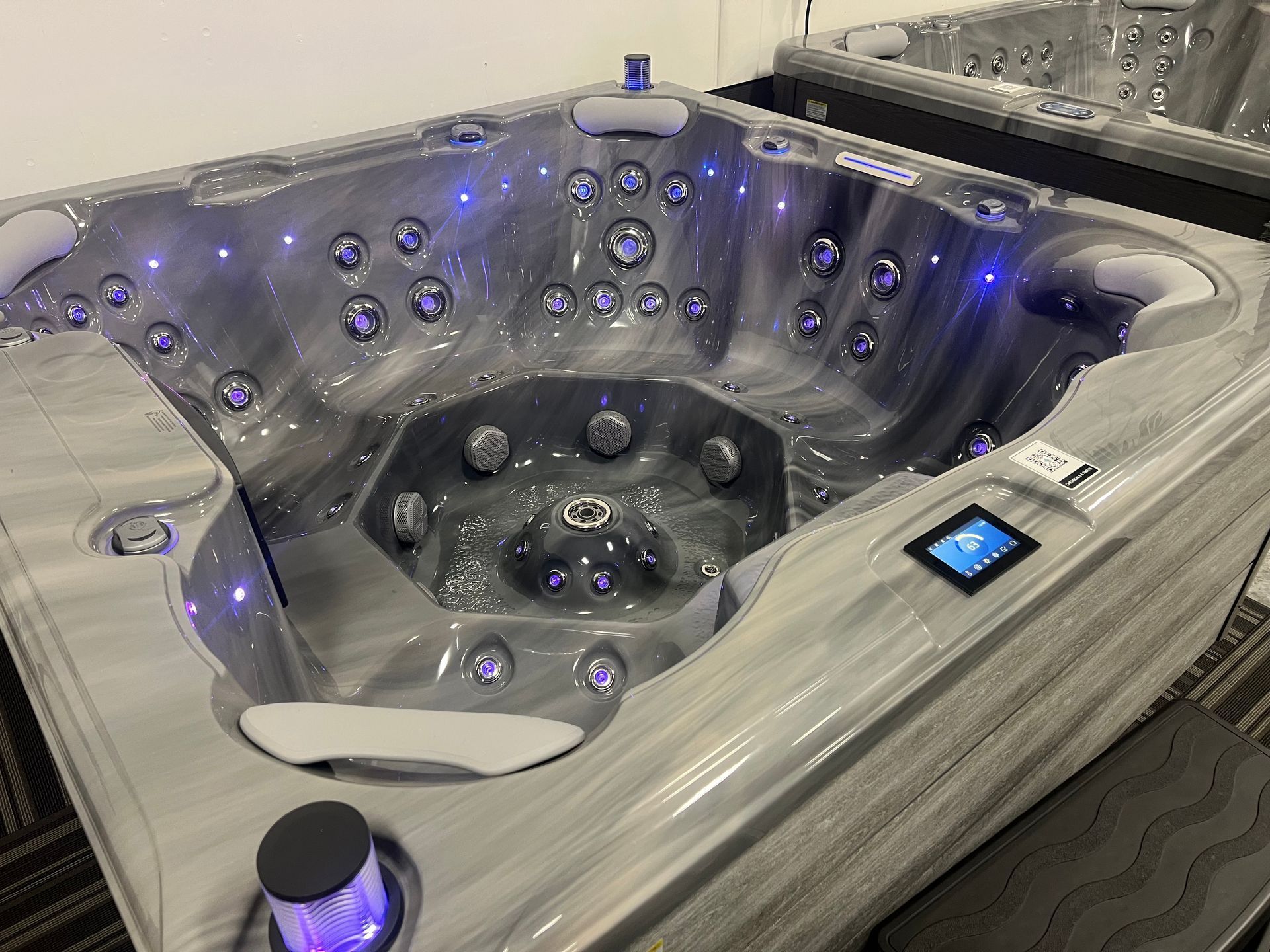 Man using a crane to lift hot tub cover on a wooden deck. White house in background.