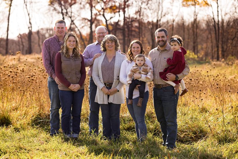 A family is sitting on a wagon in a field.