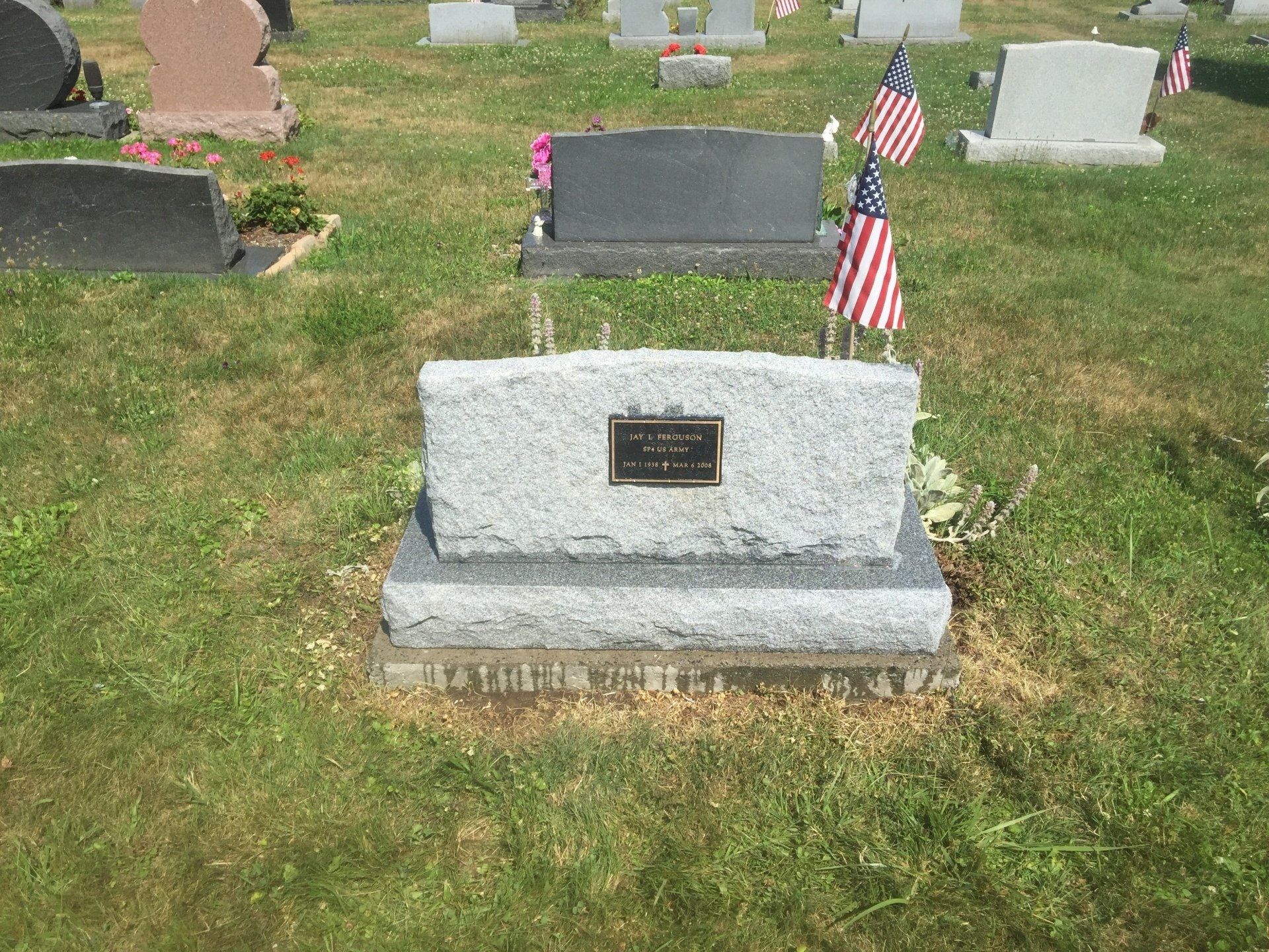 A grave in a cemetery with american flags on it.
