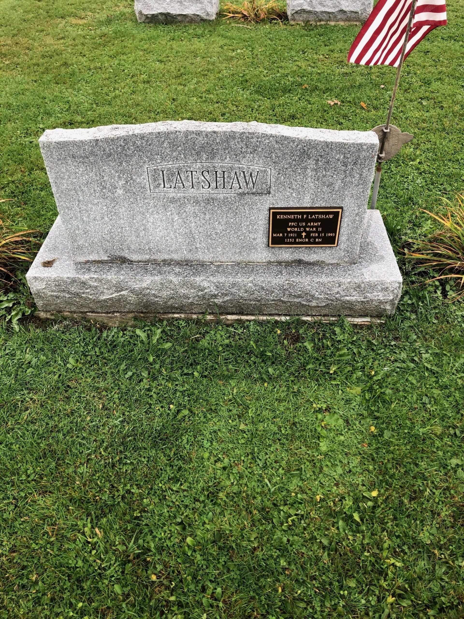 A grave in a cemetery with a flag in the grass.
