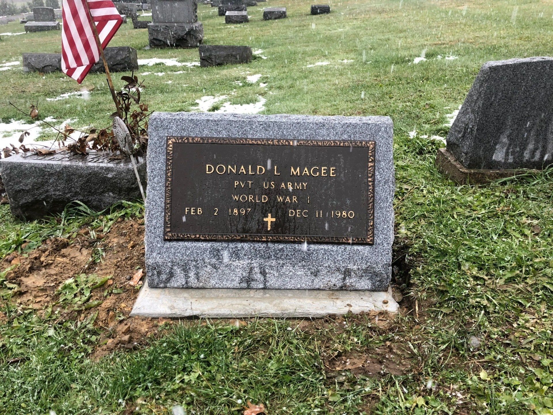 A gravestone in a cemetery with a flag in the background.