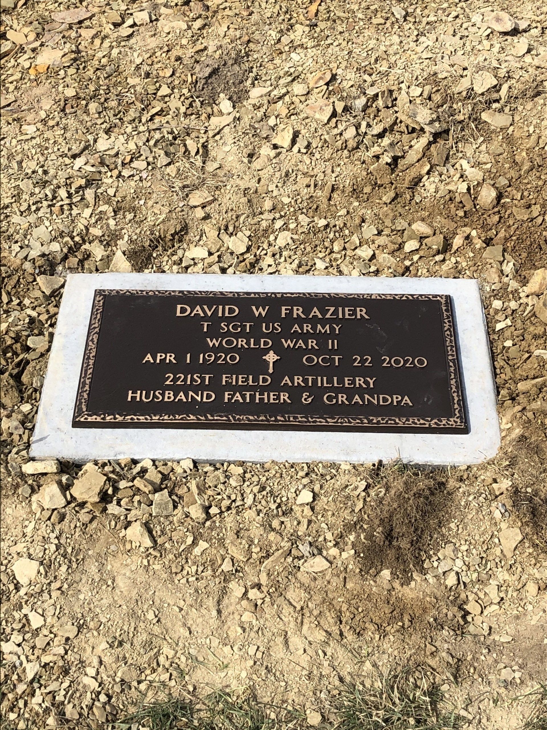 A gravestone for a soldier is sitting in the dirt.