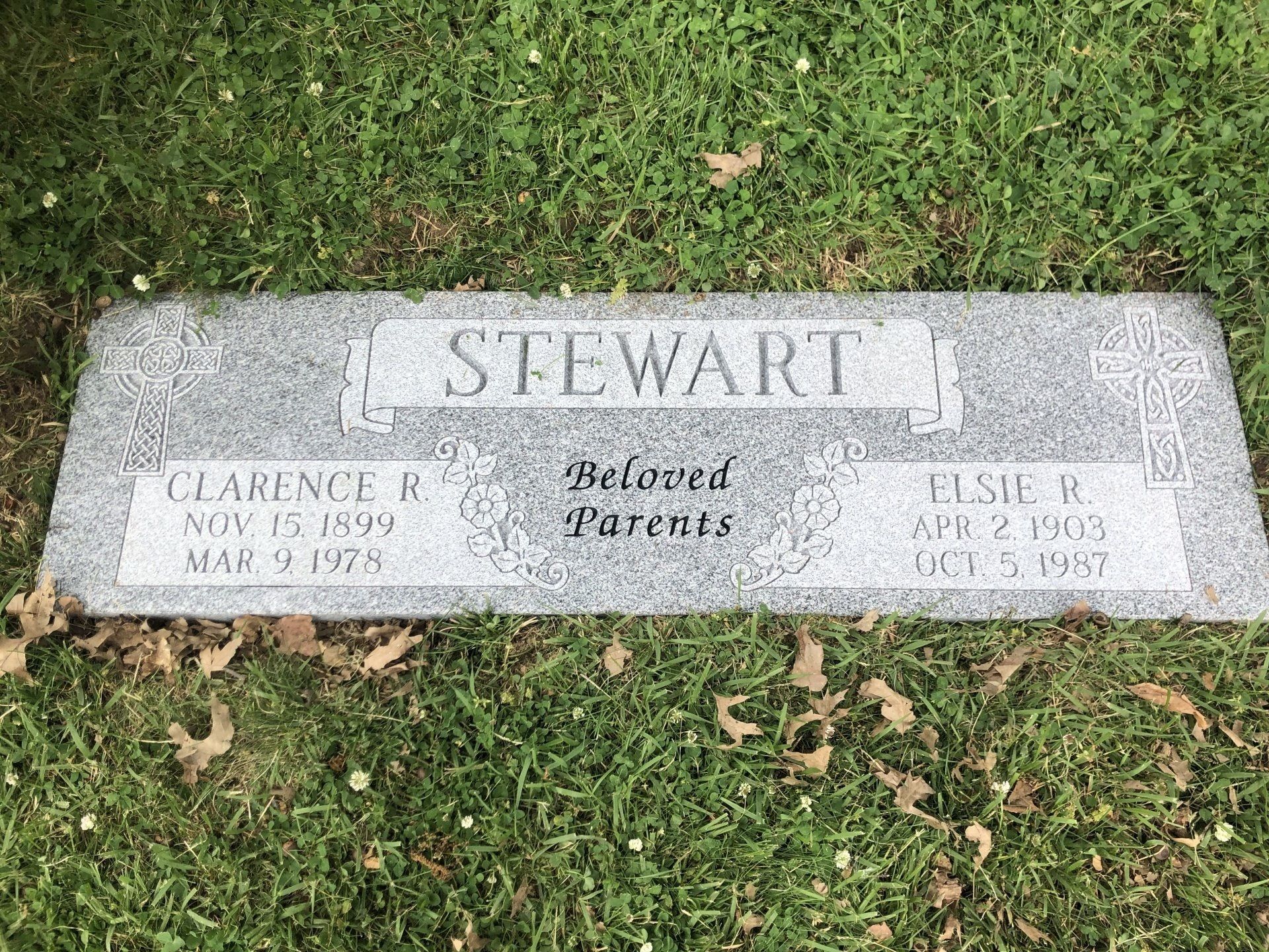 A gravestone for a man named stewart is sitting in the grass.