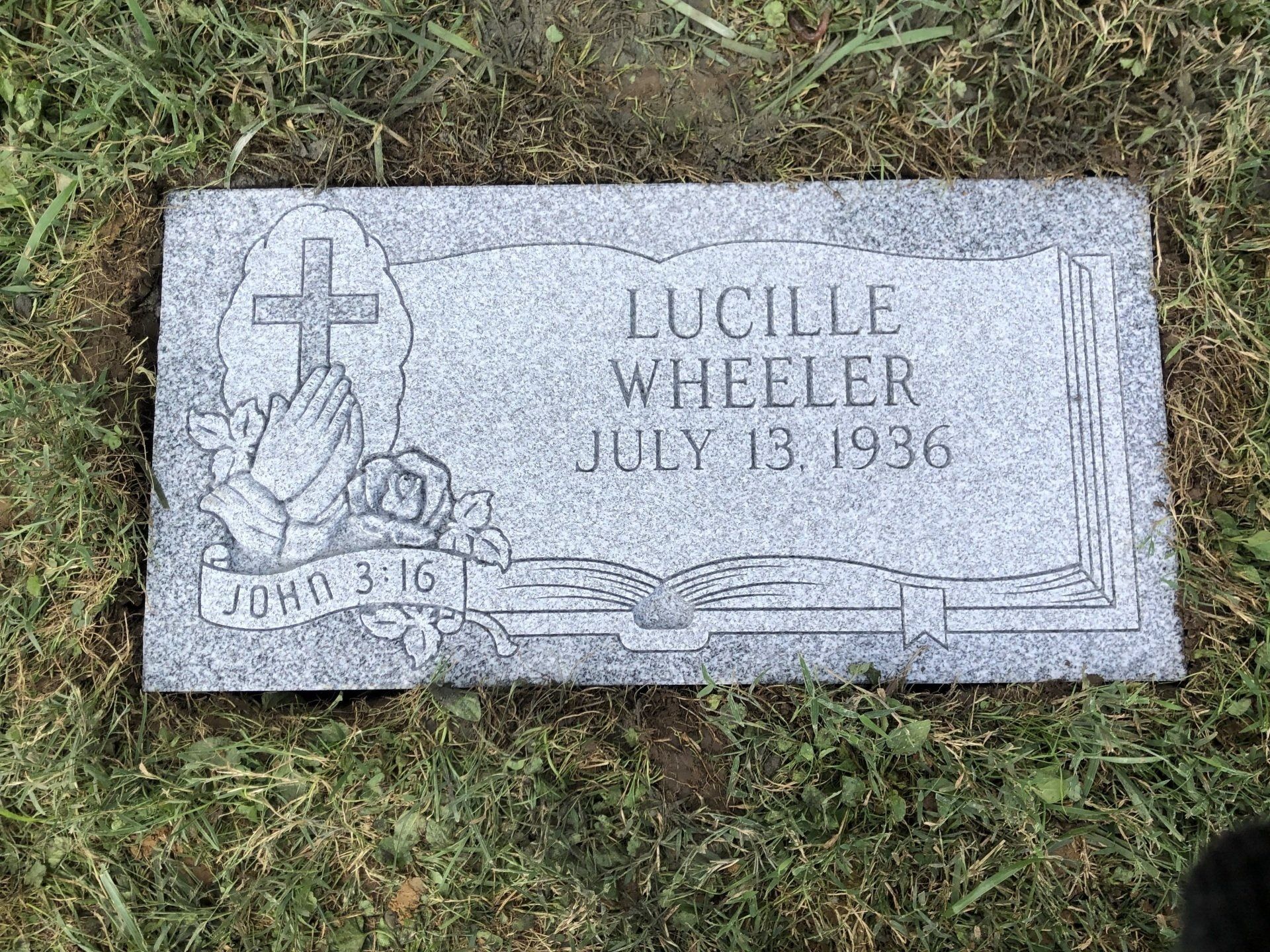 A gravestone for lucille wheeler is sitting in the grass.