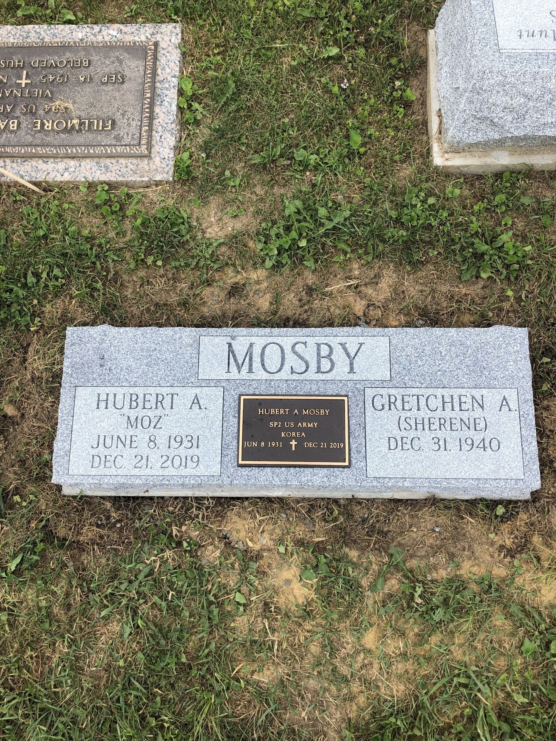 A gravestone in a cemetery with a plaque on it.