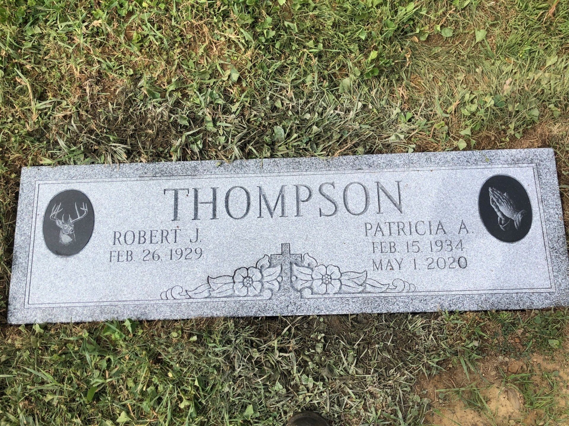 A gravestone for thompson is sitting in the grass.
