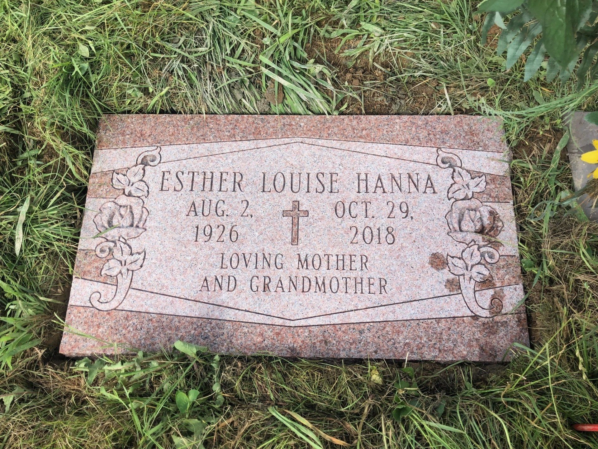 A gravestone for a woman is sitting in the grass.