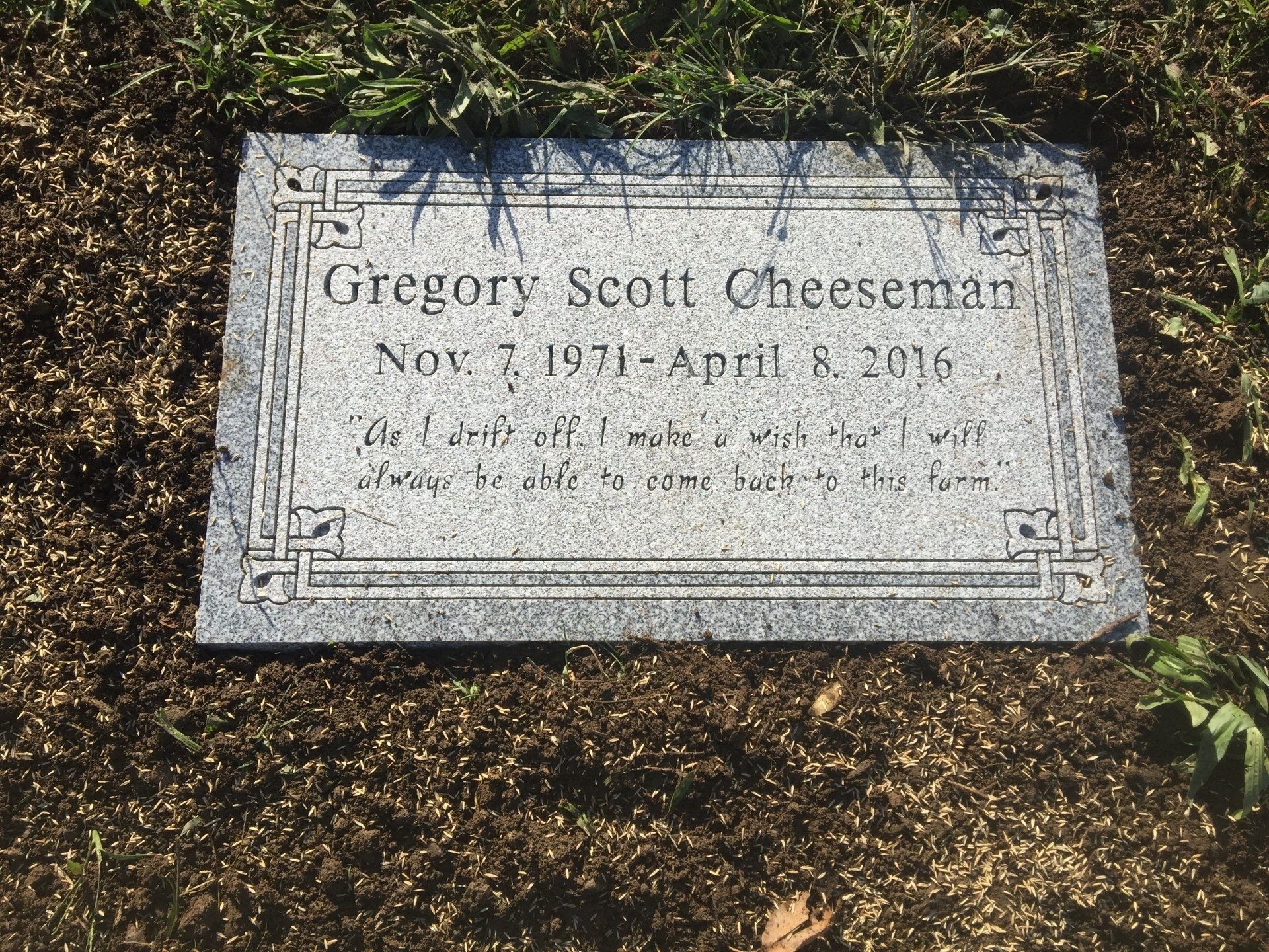 A gravestone for gregory scott cheeseman is in the grass.