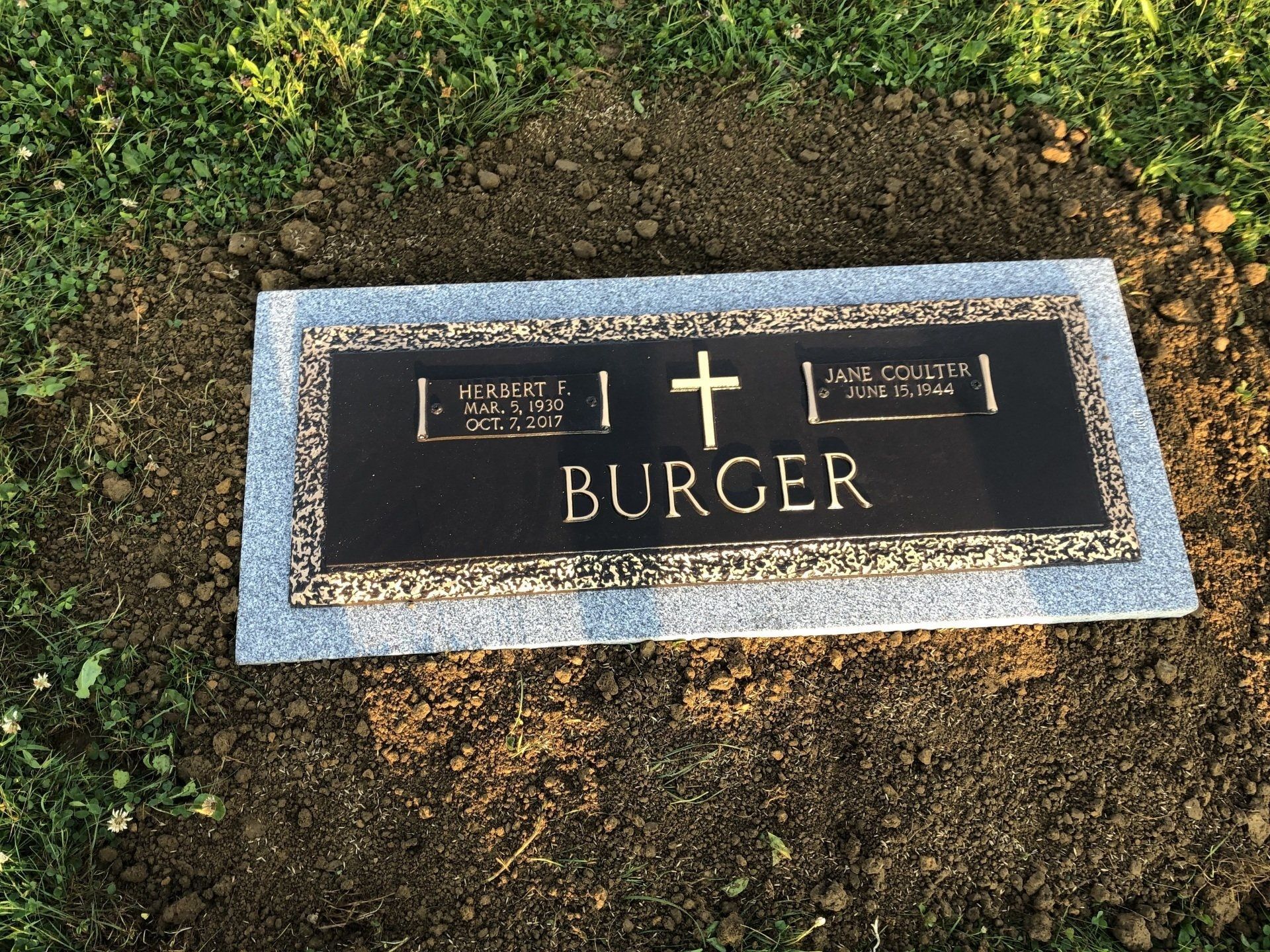 A grave marker for burger is sitting in the dirt.
