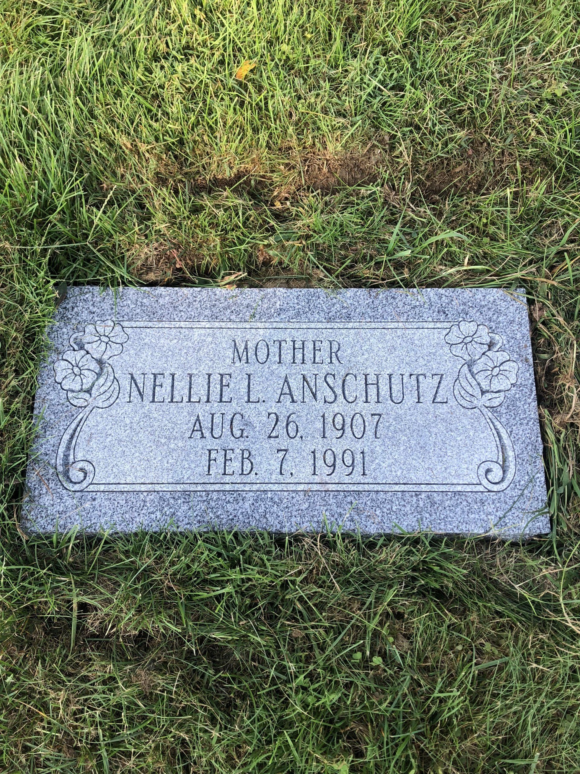 A gravestone for a woman is sitting in the grass.