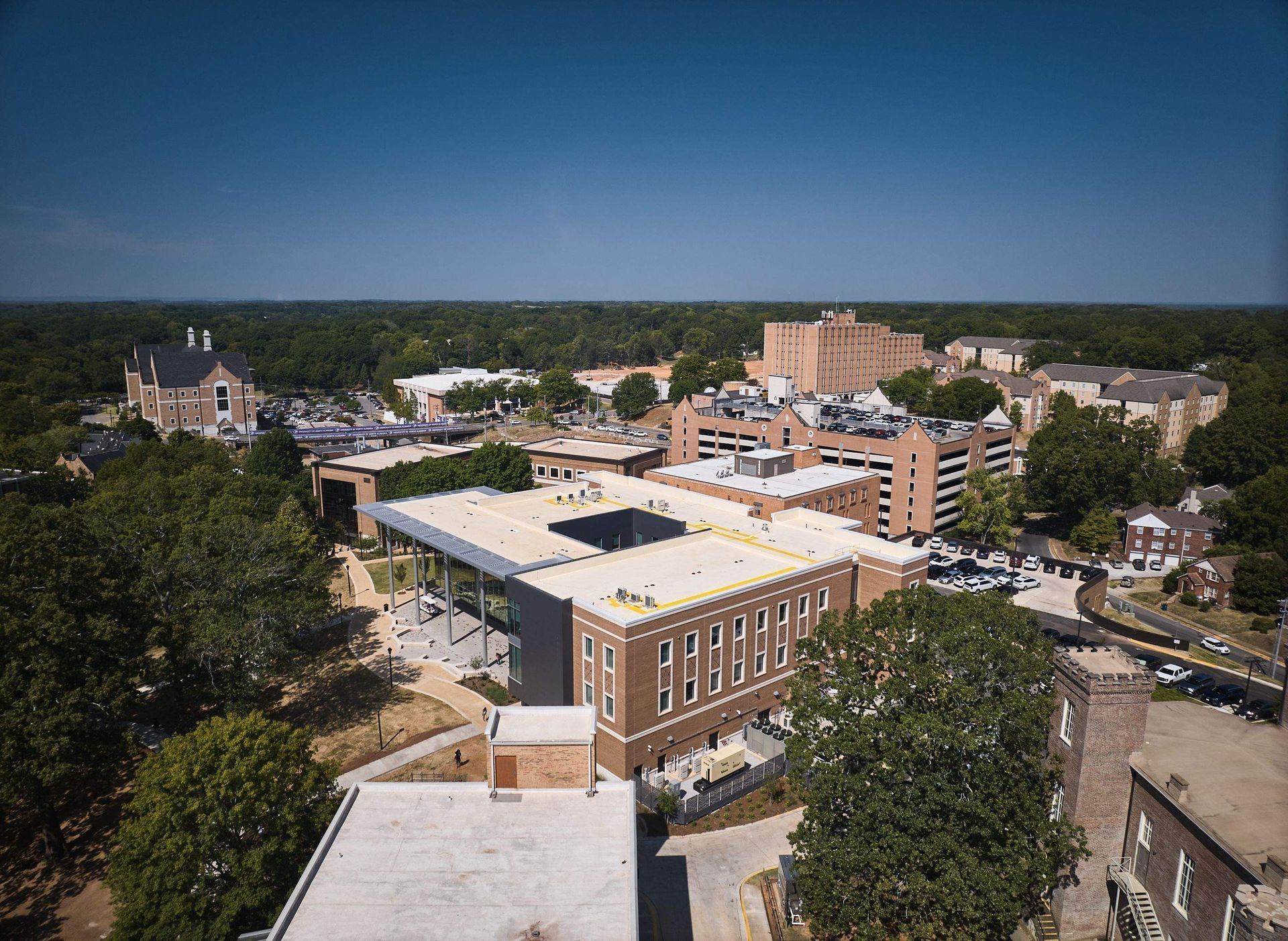 Aerial view of a campus with brick buildings, trees, and a clear blue sky.