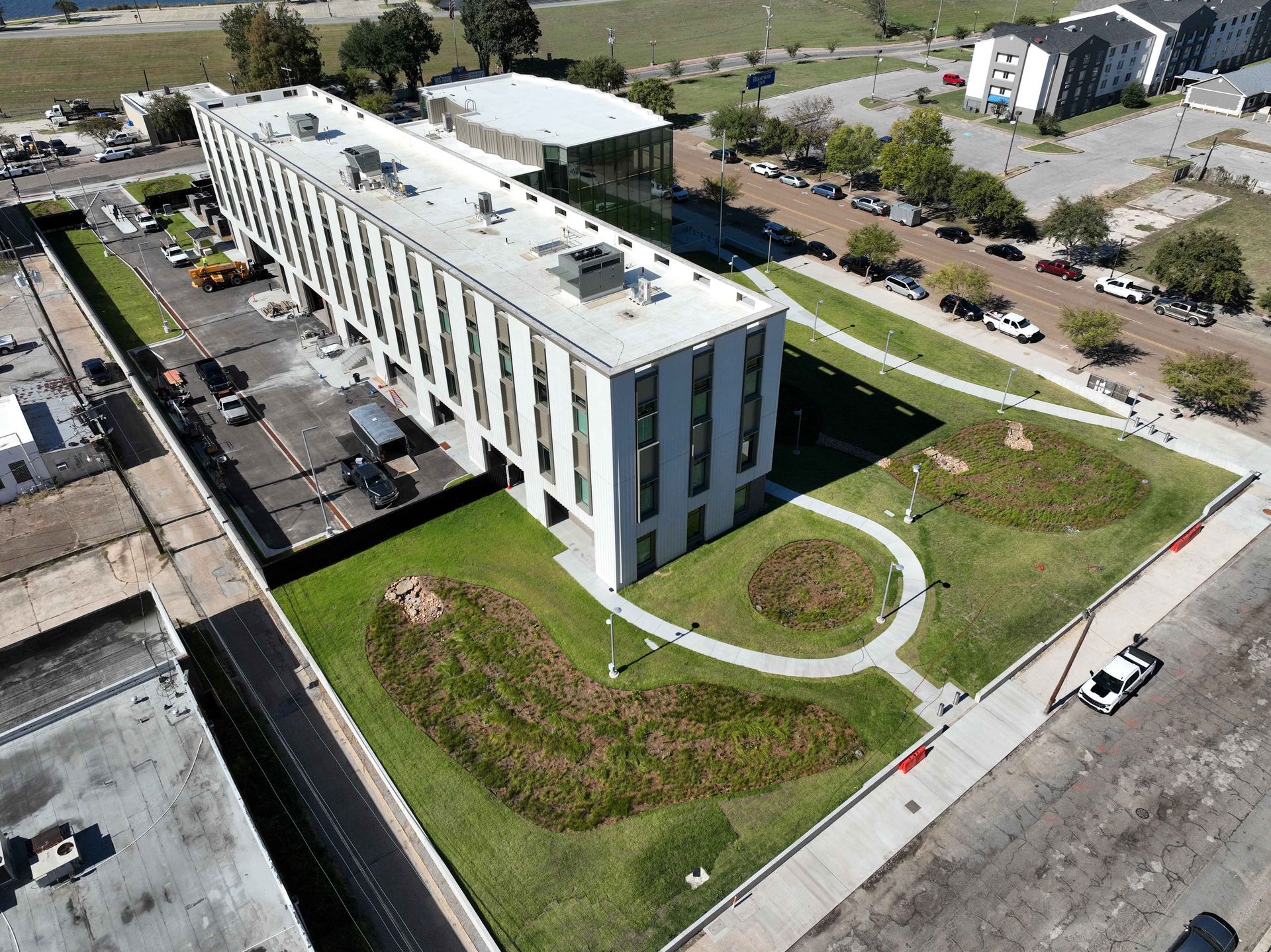 Aerial view of a modern white office building with green lawns and circular walkways.
