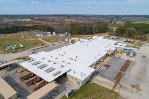 Aerial view of a large white-roofed warehouse under construction in a rural industrial area