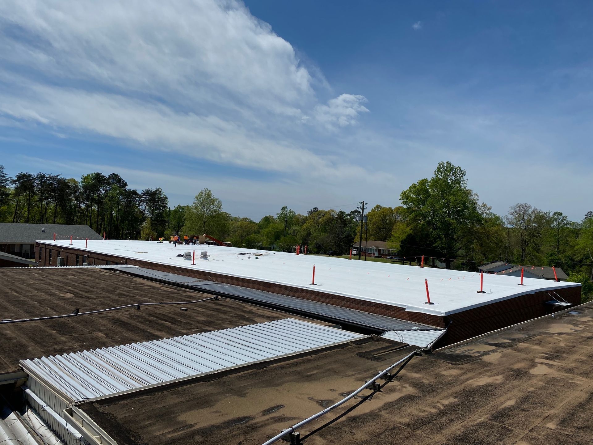 Roof under construction with white insulation sheets and orange safety cones under a blue sky