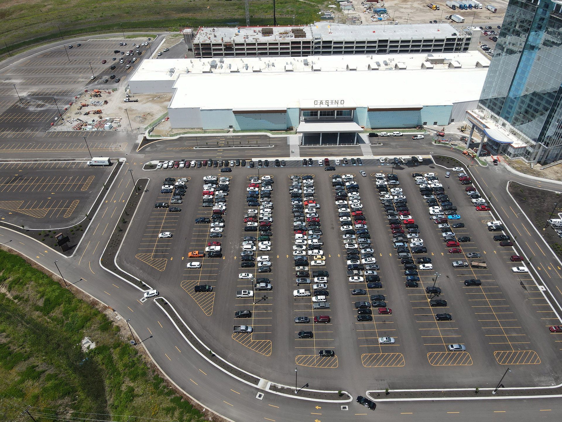 Aerial view of a large white building with a crowded parking lot and surrounding roads.