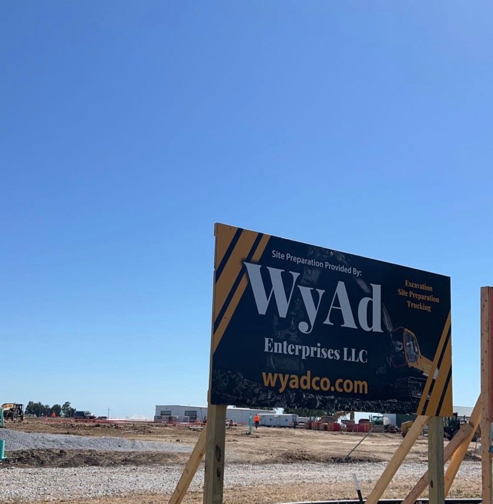 Sign for WyAd Enterprises LLC at a construction site, with blue sky background.
