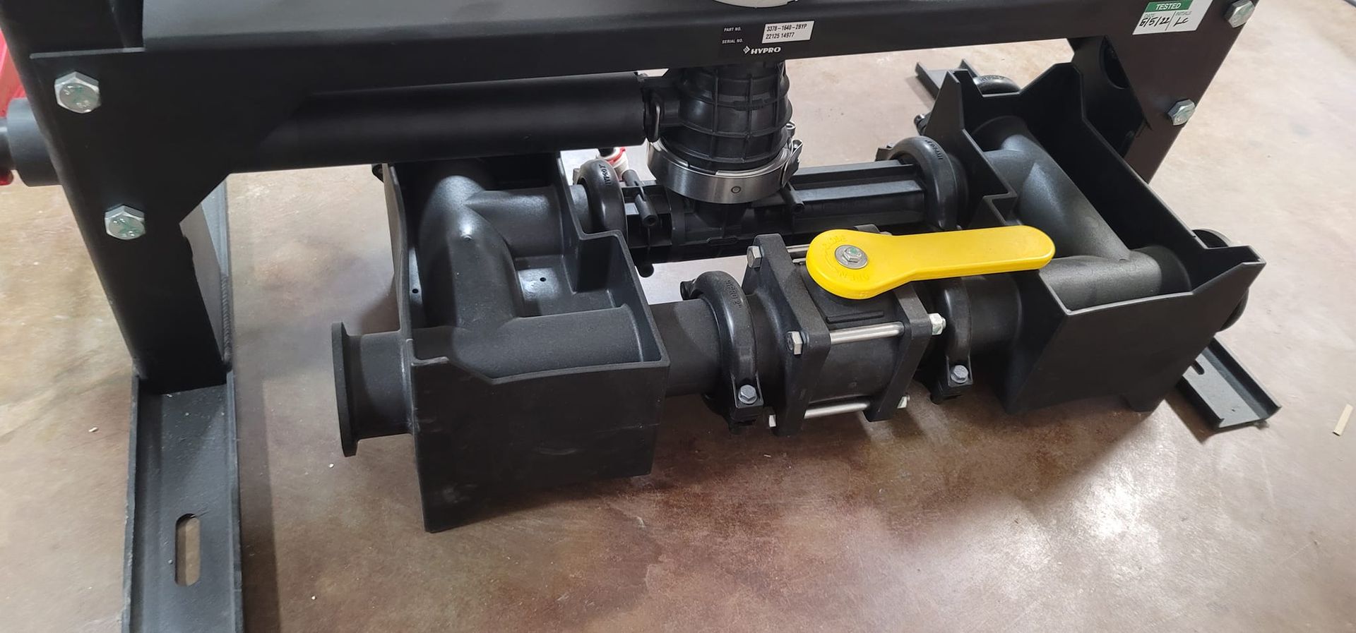 Black industrial machinery with a yellow lever, on a brown surface.