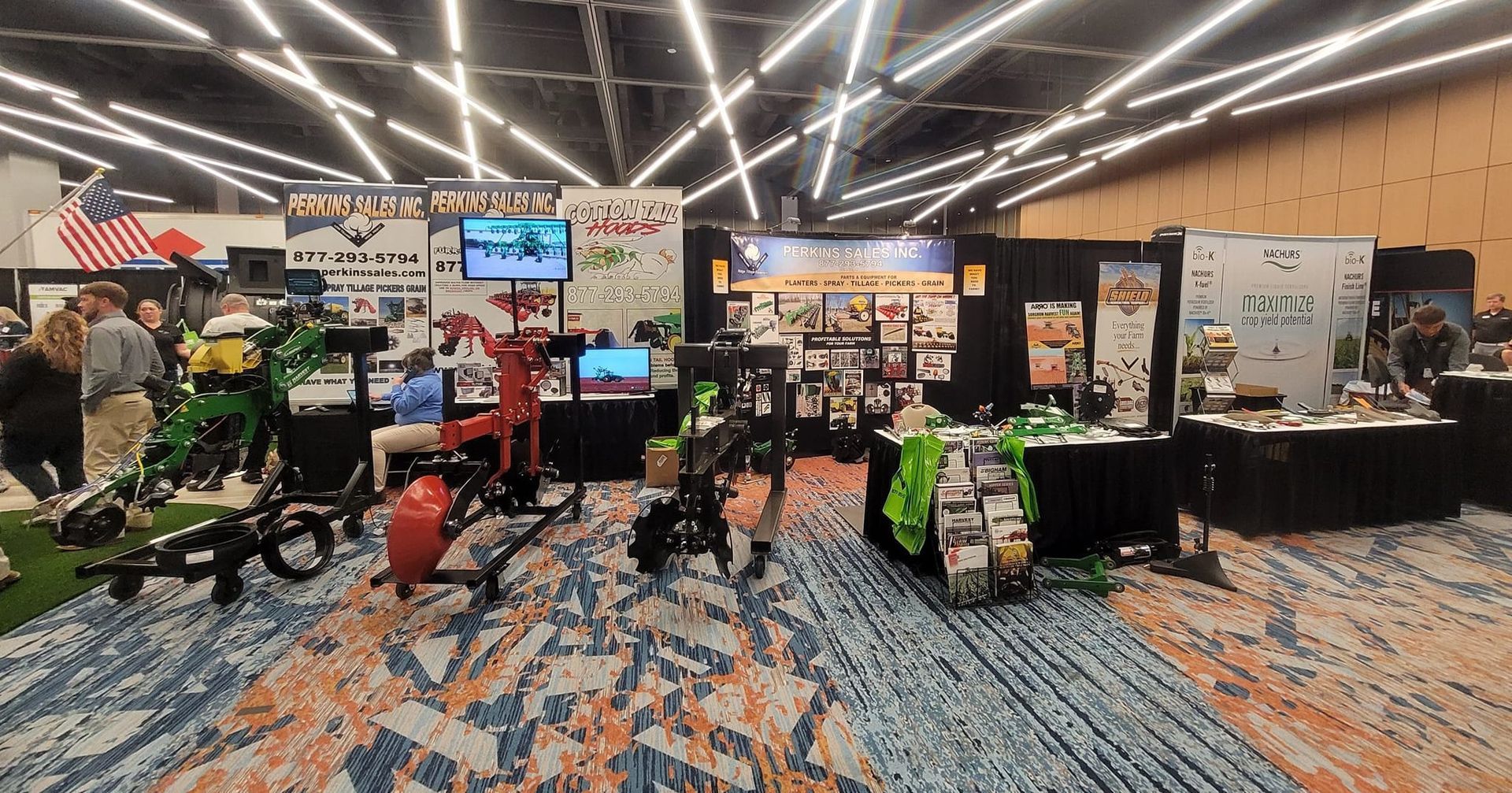 Trade show booths display outdoor gear. People browse products in a large convention hall.