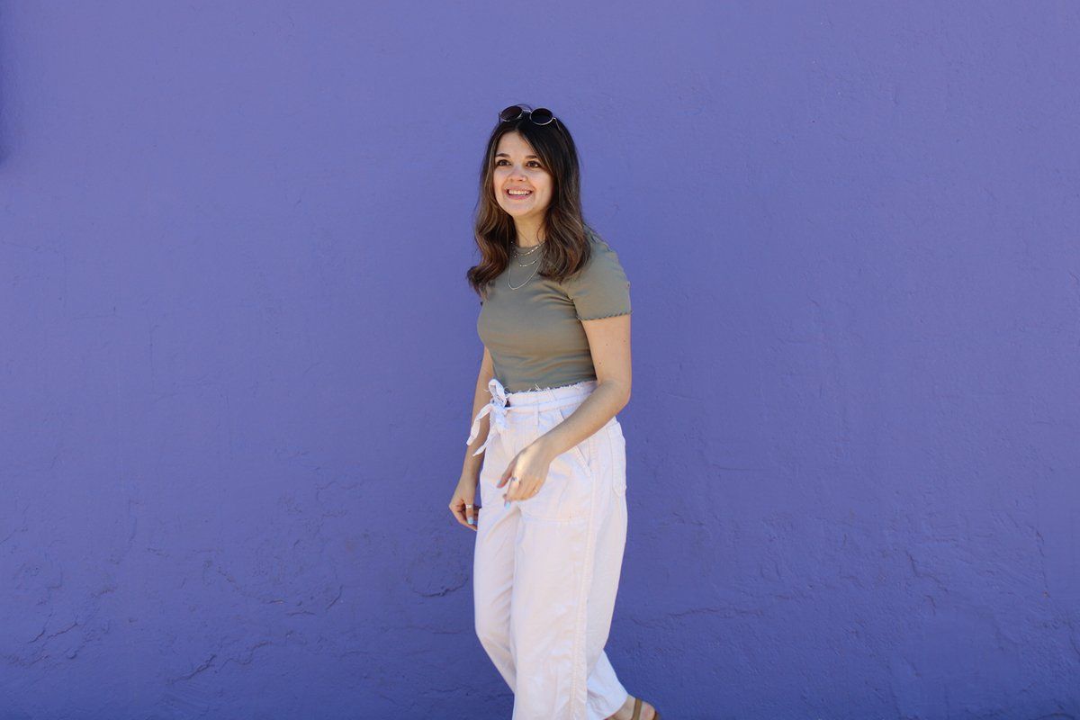 A woman is standing in front of a purple wall.