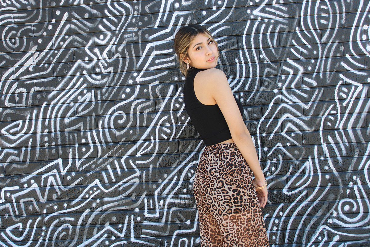 A woman is standing in front of a mural on a wall.