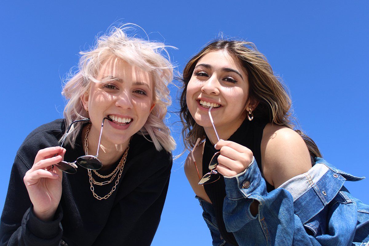 Two women are standing next to each other holding straws in their mouths.