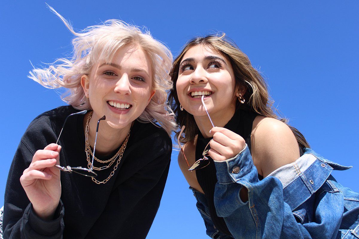 Two young women are standing next to each other and smiling.