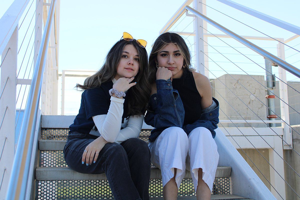 Two young women are sitting on a set of stairs.